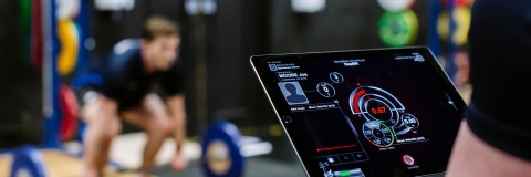 A student tracking an athlete's progress in the gym