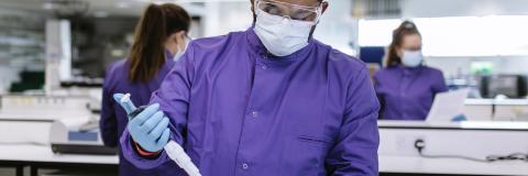 Student wearing a purple lab coat with a mask and safety goggles