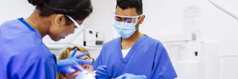 Two dental students work on patient