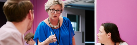 Meeting between large group in room with pink wall