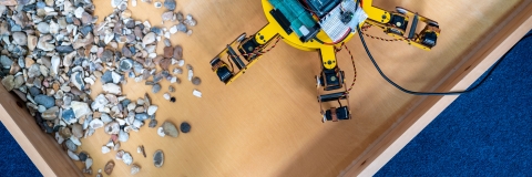 Image of yellow spider-like robot organising rocks