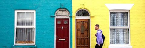 Male student outside bright coloured houses