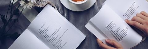 Two poetry books on a table with a cup and saucer of coffee