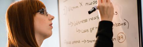 A student writing notes about criminal justice on a whiteboard