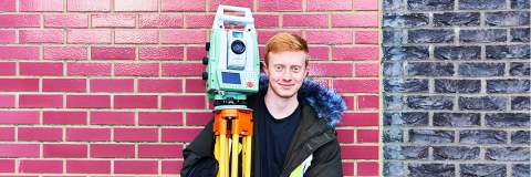 male student holding surveying equipment
