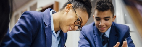 Two students smiling as they work together at a desk