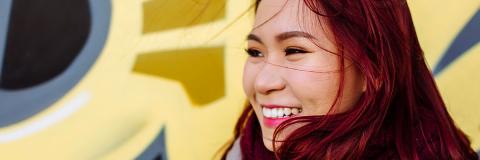 A Vietnamese student with red hair stood in front of a colourful wall