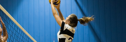 A sports student playing volleyball in a sports hall