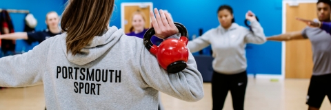  A Portsmouth Sport instructor, holding a dumbbell, teaching a fitness class