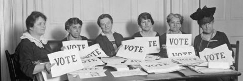 Suffragettes holding cards saying "Vote"
