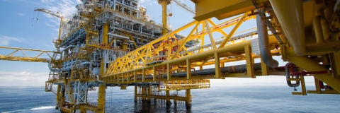 An oil rig in an ocean against a blue sky