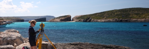 Researcher using a theodolite on the coast in Malta