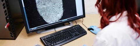 Female forensics working studying fingerprint on computer