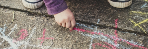 Child drawing with chalk on pavement