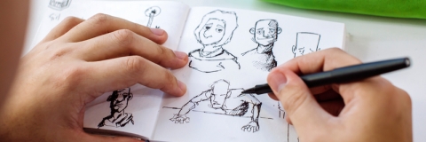 illustrator drawing in sketch book, close-up