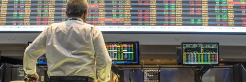 Person standing in front of screens showing financial data