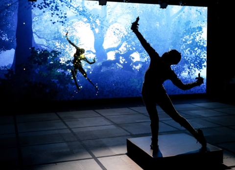 performer dancing on stage using motion capture technology, with the set designed to depict a forest