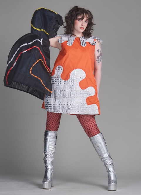 Student wearing orange and white dress made from recycled materials