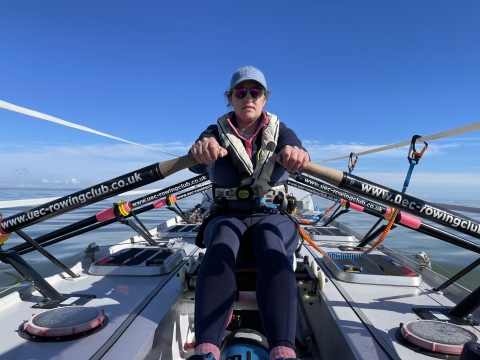 Female rowing at sea with blue sky in background