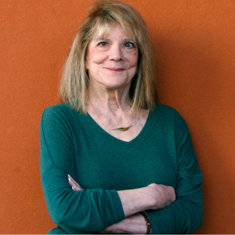 Headshot of Elizabeth Loftus wearing green jumper with necklace smiling to camera