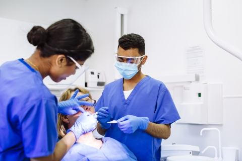Two dental students work on patient
