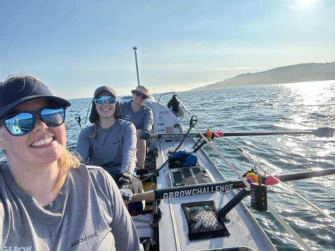 Three female rowers in their boat rowing around the UK