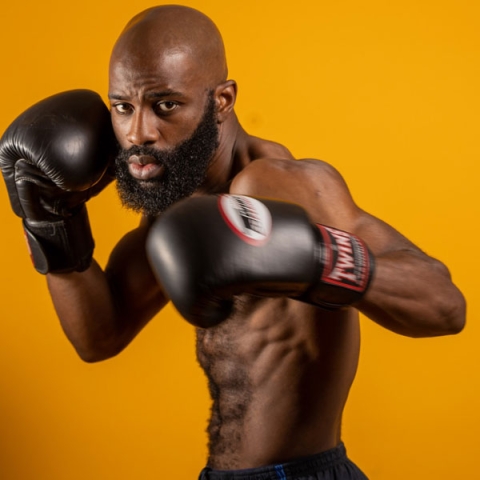 Alumnus Jonathan Francois wearing boxing gloves holding boxing stance to camera with gloves up