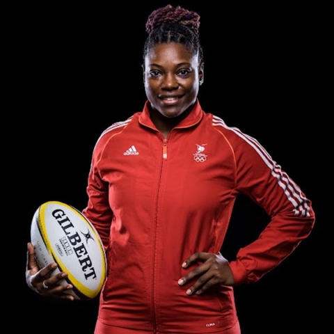 Headshot of Kanisha Vincent smiling to camera wearing red sports hoodie whilst holding a rugby ball