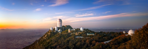 A domed building sits atop a mountain at sunset.