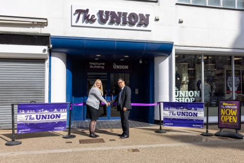 Two people shaking hands in front of the opening of the new Students Union 