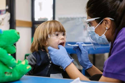 A member of the dental academy helping a child brush their teeth