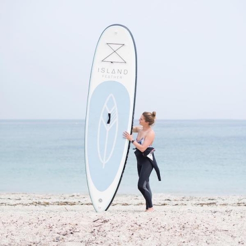A woman holding a paddleboard at the beach