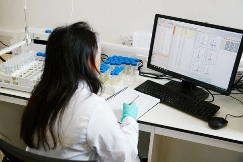 Student sitting at computer and taking notes in laboratory