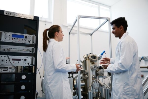Two students converse in the Molecular Beam Epitaxy Laboratory