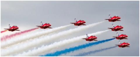 Nine red fighter jets flying in a V-shape formation 