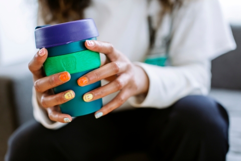 Close up of a reusable cup held by a person with painted nails
