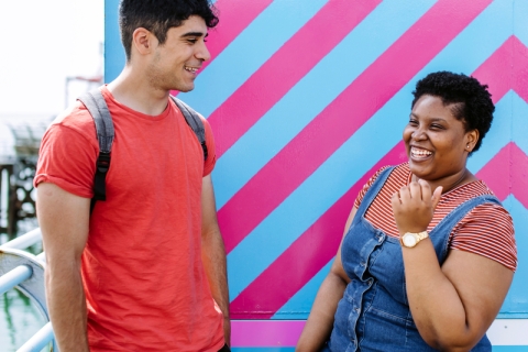 Two students smiling in front of a pink and blue striped wall