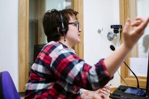 Student in headset speaks into microphone in interpreter suite