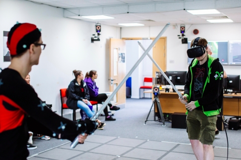 Two students using light sabres in virtual reality lab
