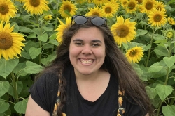 Image of Dr Laura Bower standing in front of a sunflower field. 