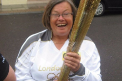 Image of Bronwin Carter holding the olympic flame smiling to camera