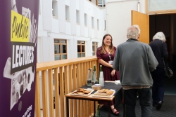 Two people entering the lecture theatre being greeted by a member of staff