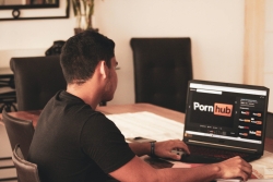 Man in front of laptop with Pornhub logo - Photo by franco alva on Unsplash