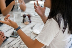 A person sat at a table talking and gesticulating