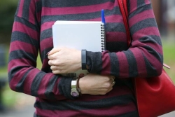 Student holding notebook close to their chest