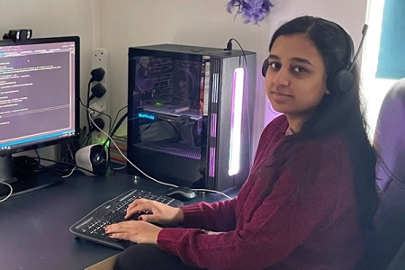 Prisha wearing headset behind the computer desk