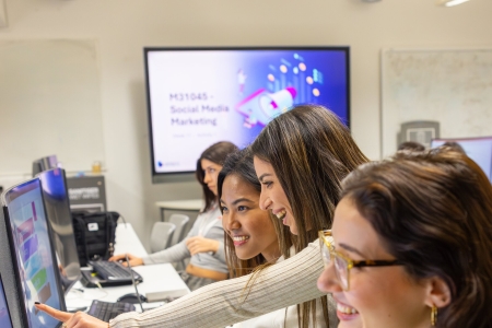Students in computer lab with lecturer assisting