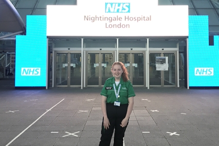 Woman in hospital uniform standing outside NHS Nightingale Hospital London