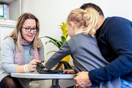 A man, woman and small child interacting with a tablet.
