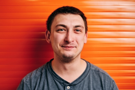 Mircea Iustin Dobrean smiling in front of an orange wall